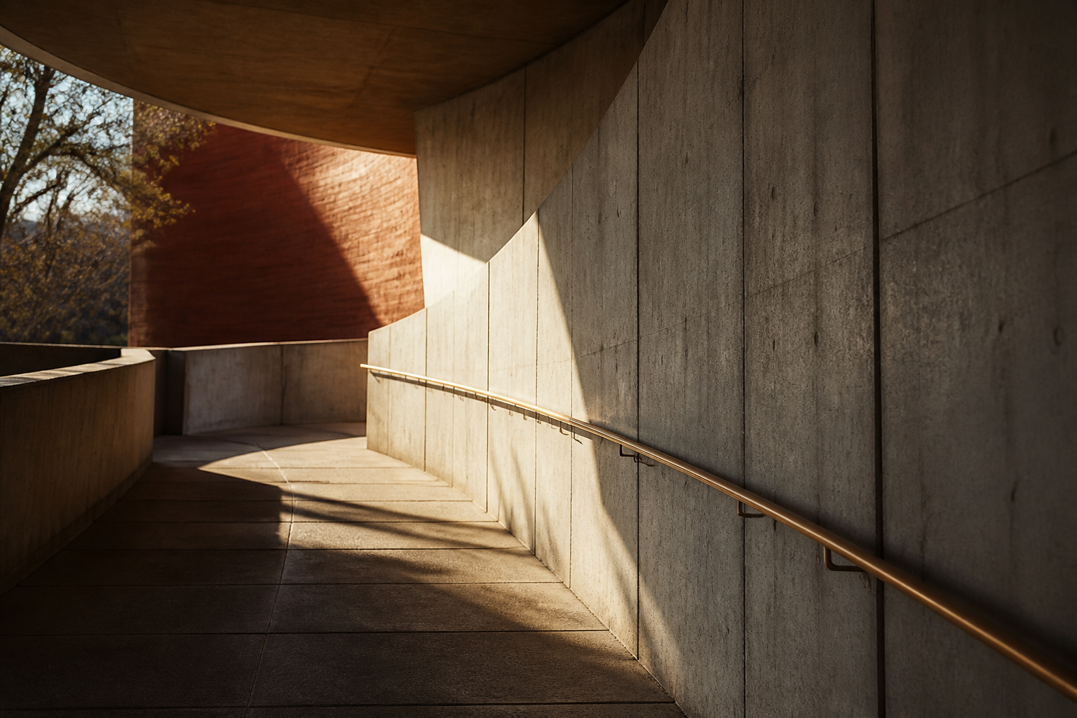 A gently sloped concrete passage with an integrated bronze handrail